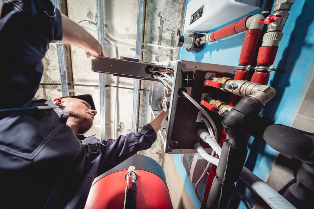 Electrician servicing electrical panel in maintenance work, ensuring proper wiring and safety.